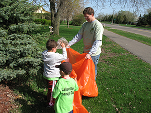 father and sons picking up trash